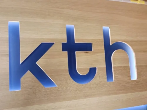 Firmenschild aus Massivholz mit eingefrästem Schriftzug "kth" für eine Steuerberatungskanzlei in Villach blau hinterleuchtet