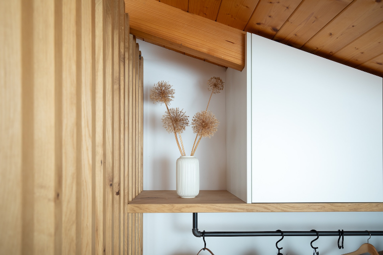 Maßgefertigte Garderobe unter einer Dachschräge mit vertikalen Eichen-Lamellen, weißem Einbauschrank und Kleiderstange im Industrial-Style (Aufstellungsort Bodensdorf)